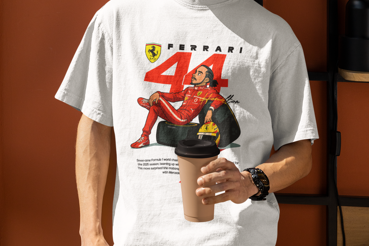 Person wearing a white t-shirt with Ferrari logo and design, holding a coffee cup against an orange wall.