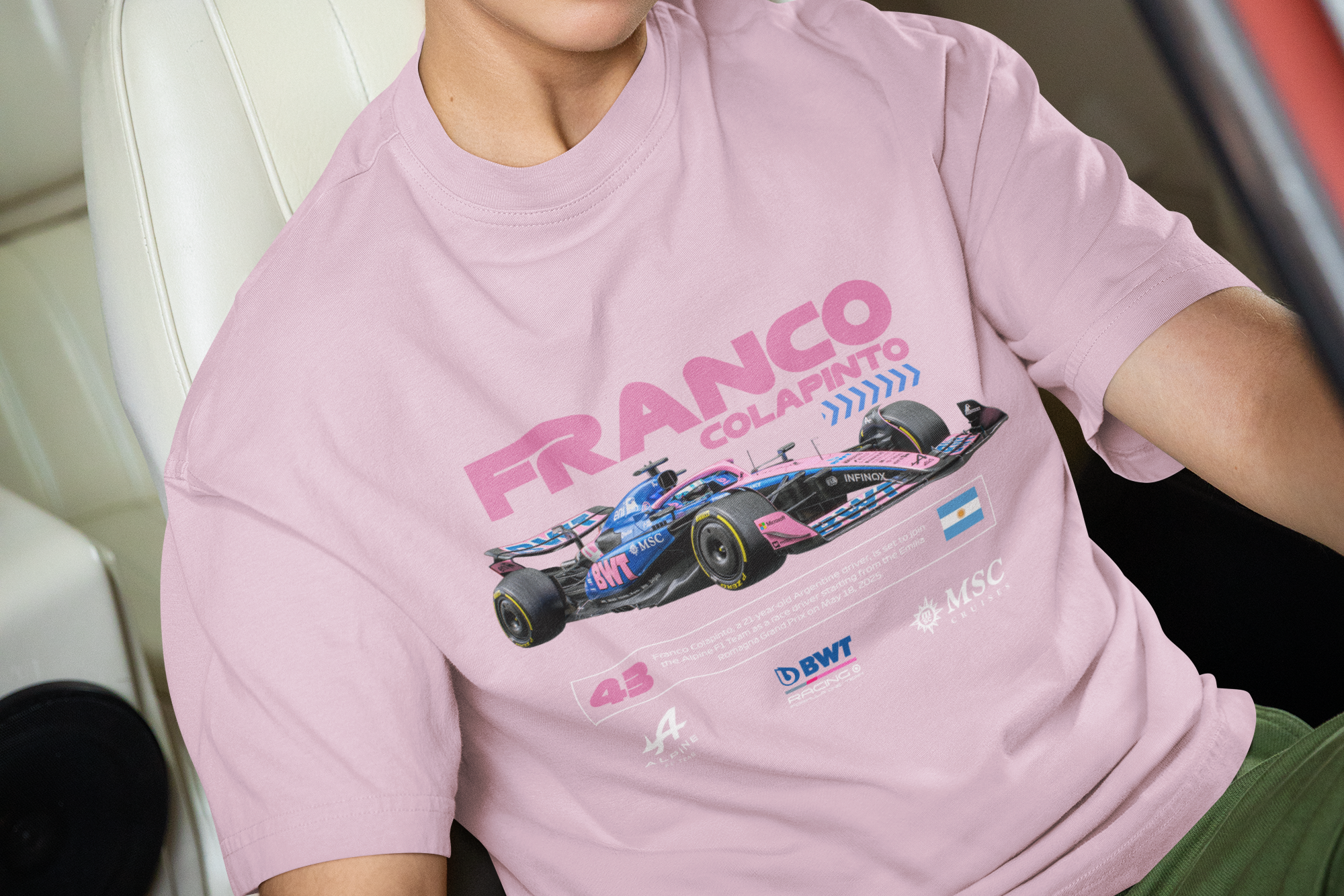Person wearing a pink 'Franco' t-shirt sitting inside a red car.